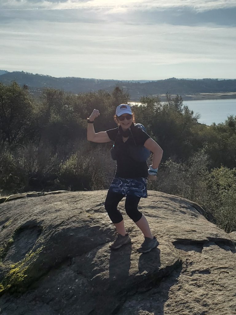 girl standing on rock flexing arm
